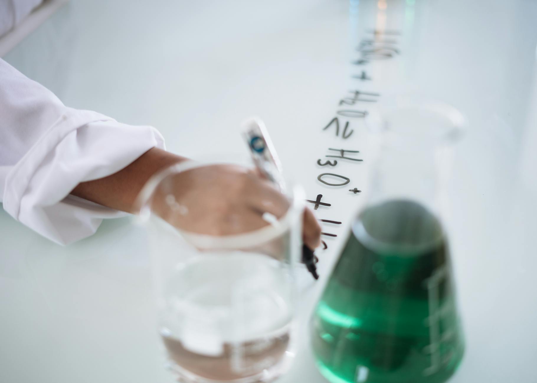 crop chemist taking science notes on whiteboard during experiment with liquids